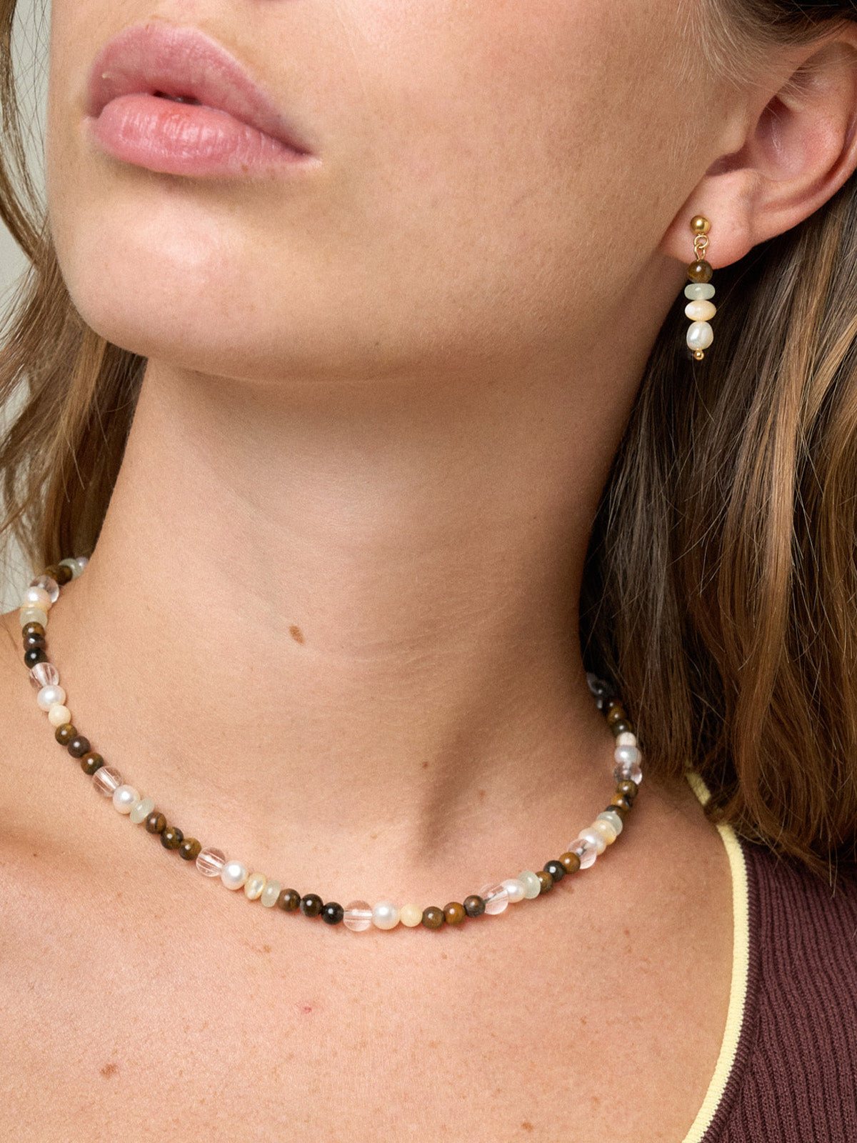 Collanina e orecchini realizzati con un’alternanza di pietre dure tra cui occhio di tigre, madreperla, new jade e perle di fiume foto indossata su modella