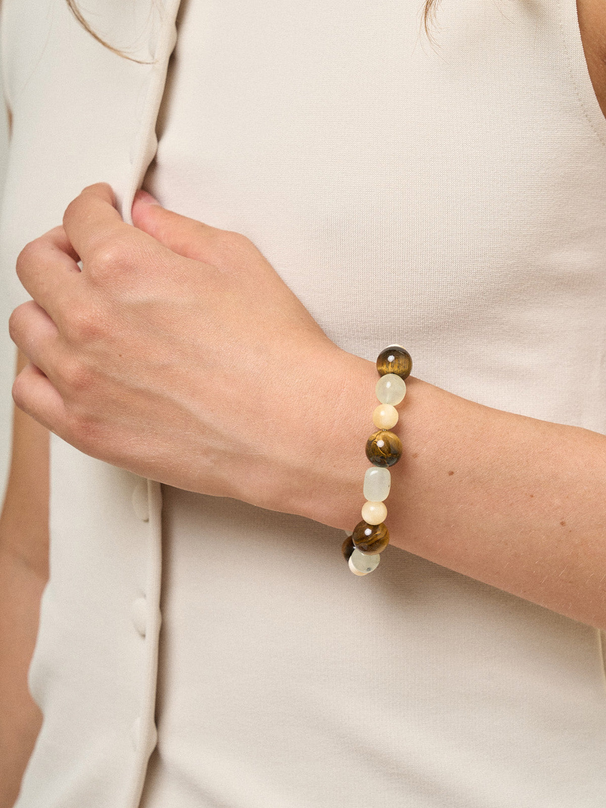 Ragazza che indossa un bracciale con occhio di tigre, madreperla e new jade, fotografia close-up.