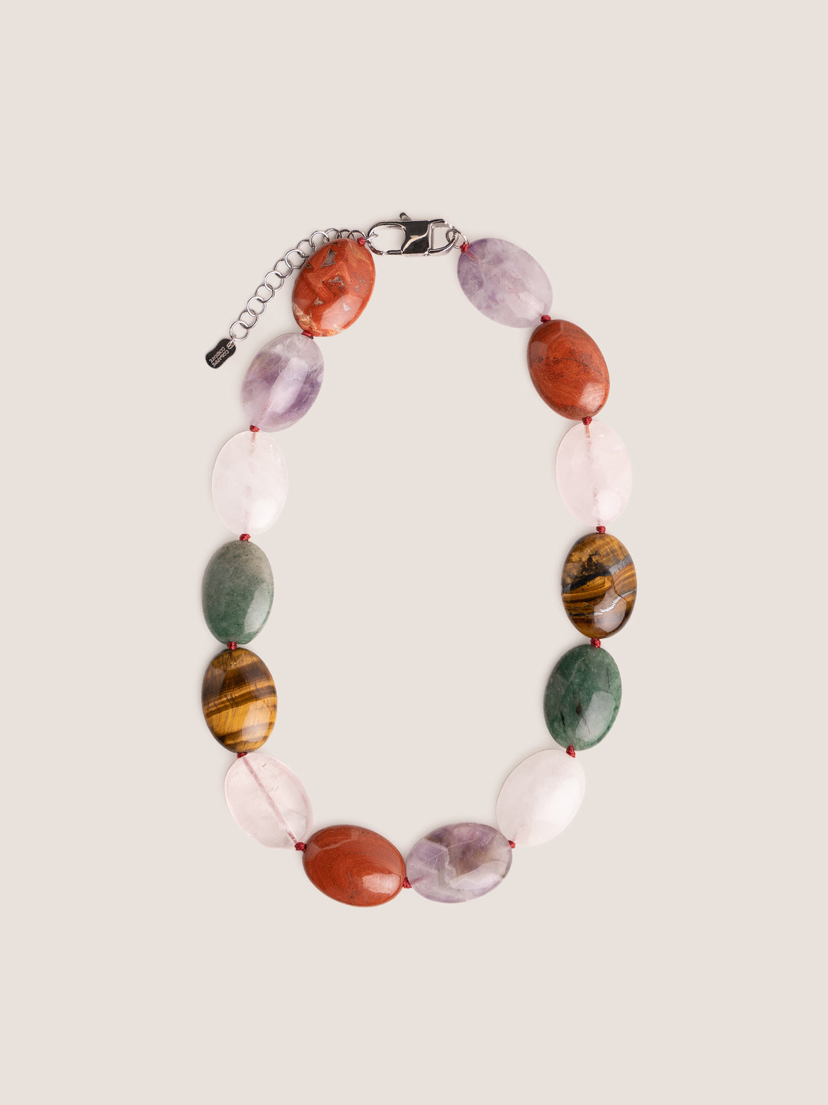 Collana Bold con pietre dure ovali in ametista, diaspro rosso e occhio di tigre, fotografia still life su sfondo neutro.